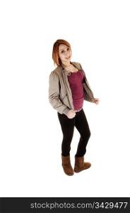 A pretty teen girl standing in the studio for white background in a grayjacket, black tights and brown boots, smiling into the camera.