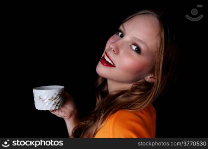 A pretty teenage girl holding a coffee cup and smiling, isolated forblack background.