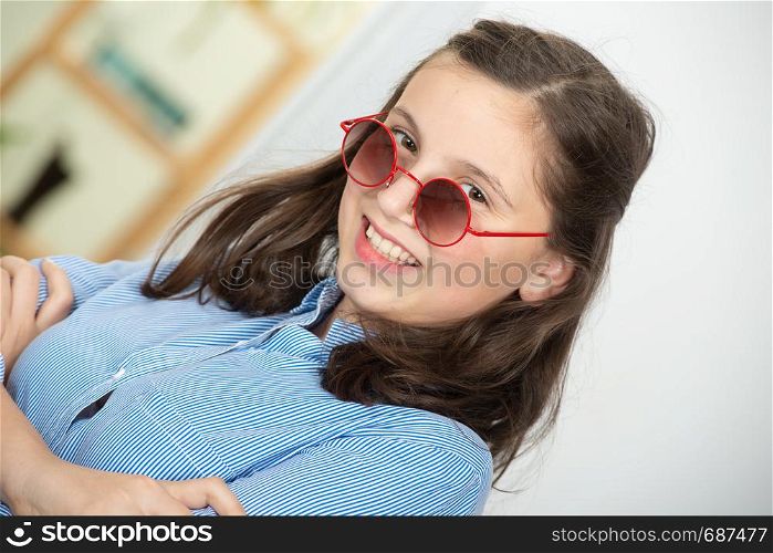 a pretty teenage girl with sunglasses and a blue shirt
