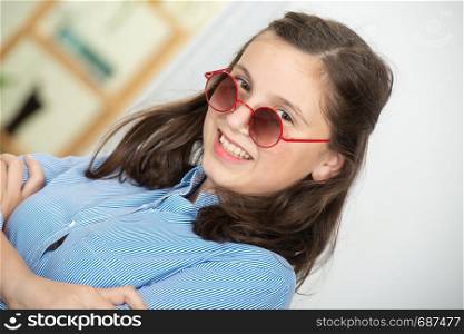 a pretty teenage girl with sunglasses and a blue shirt