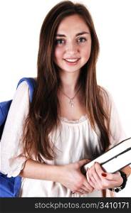 A pretty teenager in a beige blouse and a blue backpack over her shoulderand books in her hand, standing in the studio for white background.