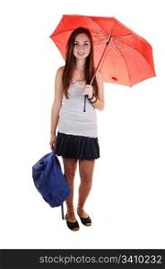 A pretty teenager in a short skirt and a blue backpack in her hand and an open umbrella over her shoulder standing in the studio for white background.