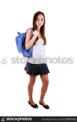A pretty teenager in a short skirt and a blue backpack over hershoulder standing in the studio for white background.