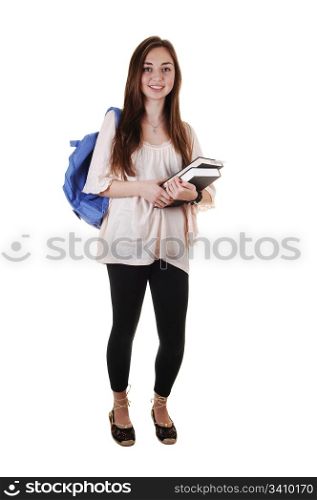 A pretty teenager in black tights and a blue backpack over her shoulderand books in her hand, standing in the studio for white background.