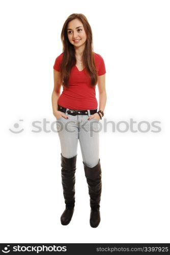 A pretty teenager standing in the studio in long boots and jeans, smilingwith her long brunette hair, on white background.