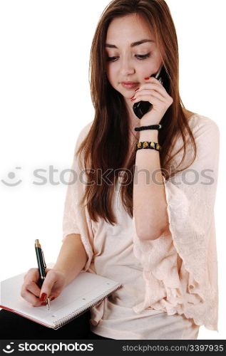 A pretty teenager talking on a cell phone with a notebook on her lapwith lovely long brunette hair for white background.