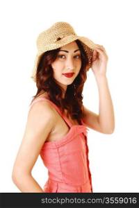 A pretty woman in a pink dress wearing a straw hat, with long brunettehair, in portrait shoot for white background.