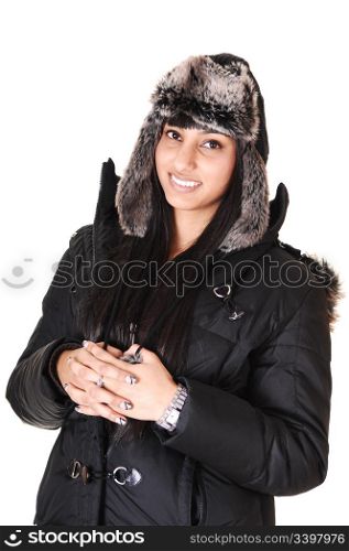 A pretty woman in a winter coat and an fur cap standing in the studiosmiling into the camera, over white background.