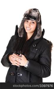 A pretty woman in a winter coat and an fur cap standing in the studiosmiling into the camera, over white background.