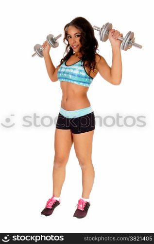 A pretty woman in black shorts and turquoise sports bra standing isolated for white background lifting two dumbbell&rsquo;s.