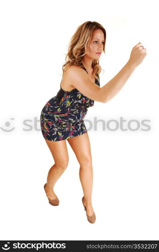 A pretty woman running in the studio for white background in a darkblue dress, with her long blond hair.