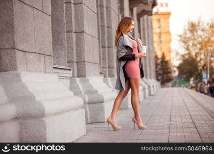 A pretty woman with a coffee to go against urban scene.