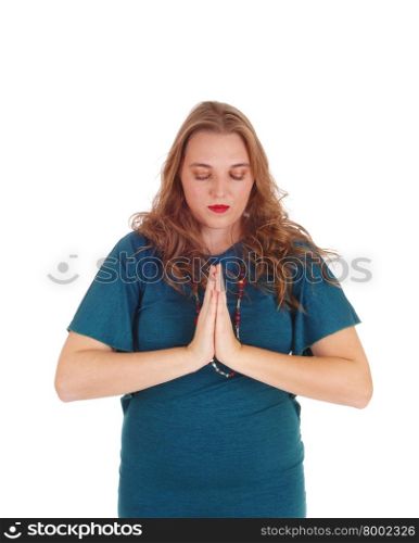 A pretty woman with her hands folded standing isolated for whitebackground praying with her eye&rsquo;s closed.