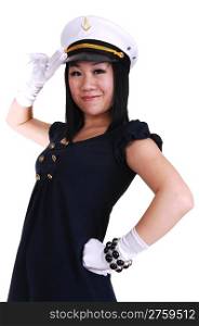 A pretty young Asian woman, in a sailor uniform, in white gloves, and a sailor cap, standing saluting in the studio.