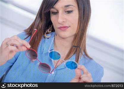 a pretty young brunette choosing a pair of glasses
