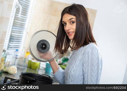 a pretty young brunette woman cooking in the kitchen