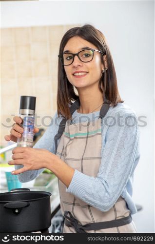 a pretty young brunette woman cooking in the kitchen