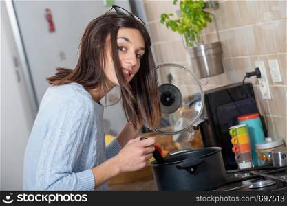 a pretty young brunette woman cooking in the kitchen