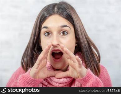 a pretty young brunette woman with hands around her mouth