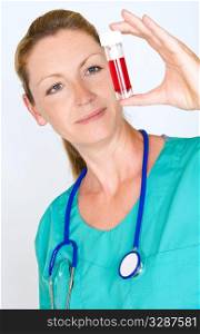 A pretty young female doctor in scrubs with a stethoscope examines a blood sample intently