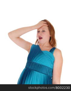 A pretty young girl in a blue dress is shocked with her hand on her foreheadan open mouth, isolated for white background.