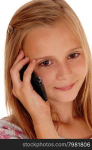 A pretty young girl with blond hair standing in closeup for white background smiling and talking on her cell phone.