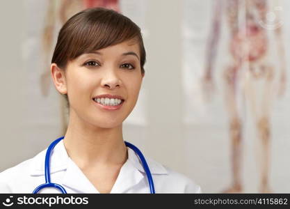 A pretty young nurse with a stethoscope shot in a hospital with human anatomy charts out of focus behind her.