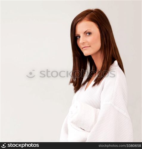 A pretty young woman in a bathrobe isolated on white