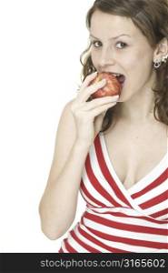 A pretty young woman in a red and white stripy top eats a red apple