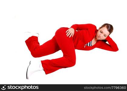 A pretty young woman in a red track suit and white boots lying in the studioon the floor and relaxing, for white background.