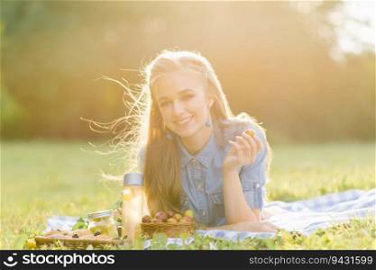 A pretty young woman is resting, lying on a blanket. Summer picnic in the park