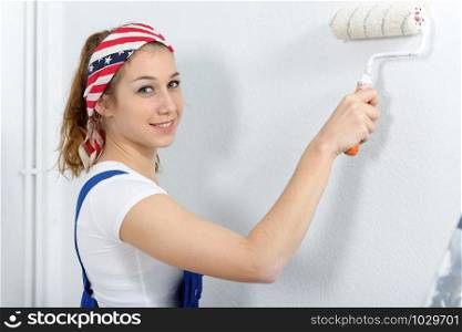 a pretty young woman paints the wall white color