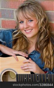 A pretty young woman resting on an acoustic guitar