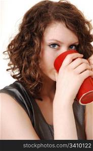 A pretty young woman thinking coffee from a big red mug, forwhite background.
