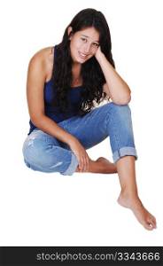 A pretty young woman with long brunette hair and jeans sittingon the floor, smiling into the camera, for white background.