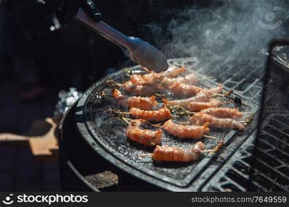 A professional cook prepares shrimps on the grill outdoor, food or catering concept. A professional cook prepares shrimps