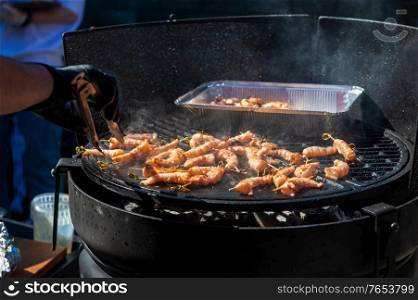 A professional cook prepares shrimps on the grill outdoor, food or catering concept. A professional cook prepares shrimps
