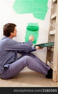 A professional painter painting with a large roller brush