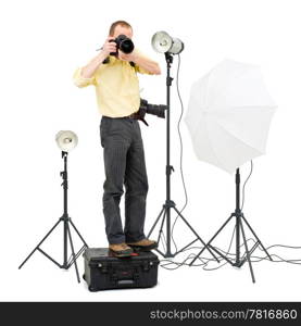 A professional photographer standing on a flight case to get a higher angle in a studio, surrounded by three strobes