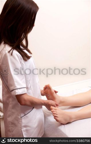 A professional young female masseur giving a foot massage