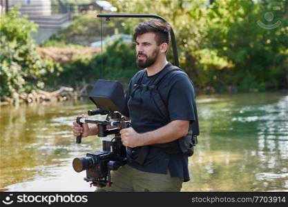 a professionally equipped cameraman shoots in the water surrounded by beautiful nature