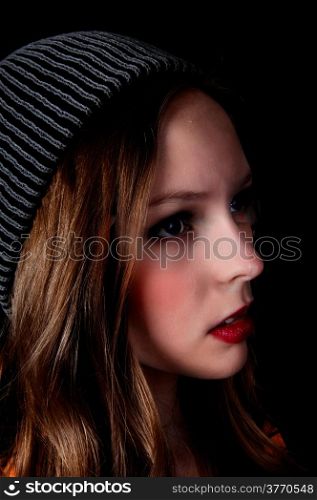 A profile portrait picture of a teenage girl wearing a knitted hat, isolated for black background.