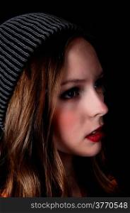 A profile portrait picture of a teenage girl wearing a knitted hat, isolated for black background.