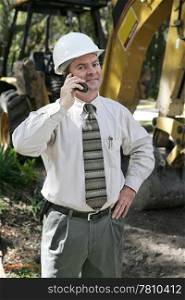A proud, confident engineer on the construction site, talking on the telephone.