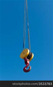 A pulley and hook hoist mechanism hanging from a crane