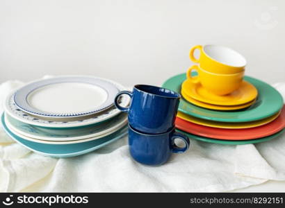 A pyramid of brightly colored bowls, plates and cups of different sizes and colors on the kitchen table. Scandinavian style, minimalism. Preparation for dinner with loved ones. A pyramid of brightly colored bowls, plates and cups of different sizes and colors on the kitchen table. Scandinavian style, minimalism. Preparation for dinner with loved ones.t