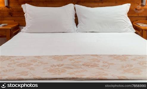 A queen sized bed with white bed sheets and two pillows