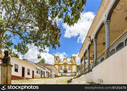 A quiet historic cobblestone street in the city of Tiradentes in Minas Gerais with colonial houses and a baroque church in the background. Quiet historic cobblestone street in the city of Tiradentes with houses and church