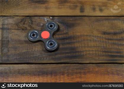 A rare handmade wooden fidget spinner lies on a brown wooden background surface. Trendy stress relieving toy