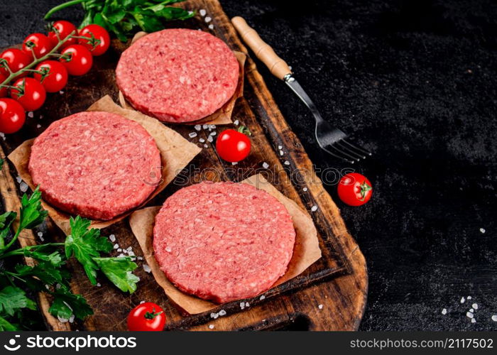 A raw burger on a tomato cutting board. On a black background. High quality photo. A raw burger on a tomato cutting board.